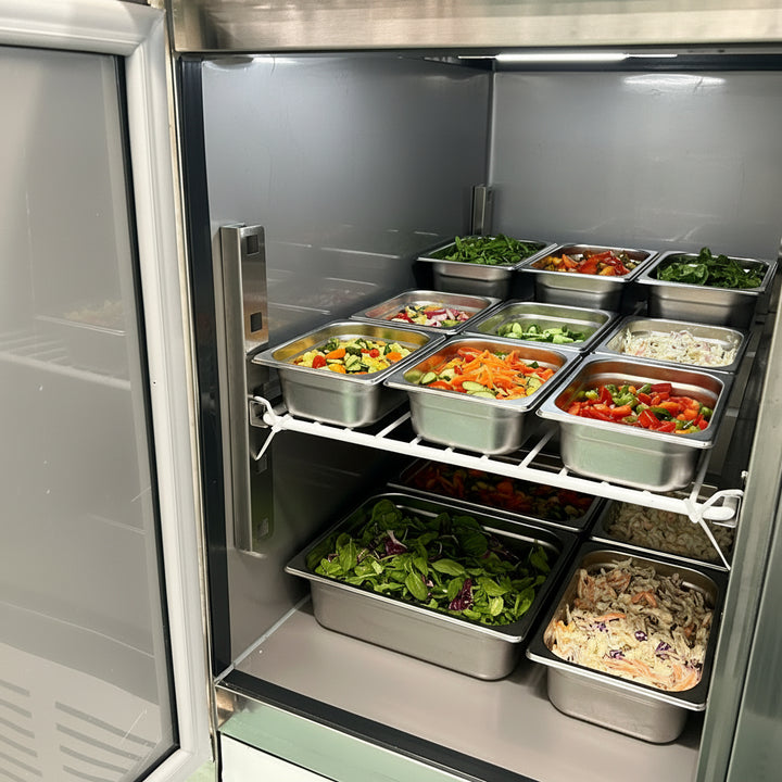 Interior view of KRD 2 Door Saladette Counter Fridge with chopping board 240L showcasing stainless steel containers filled with fresh vegetables.