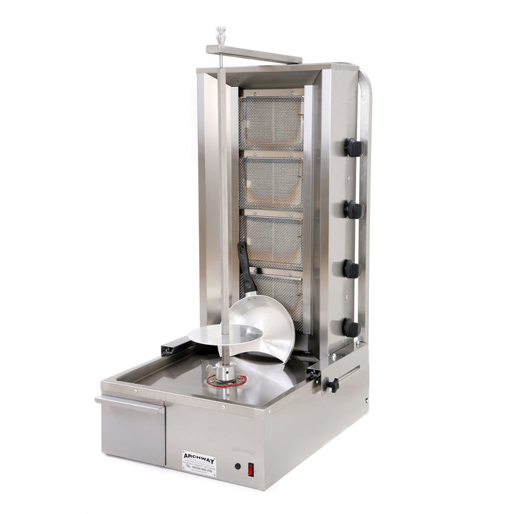 A commercial kebab grill machine with four burners, made of stainless steel, featuring a large round top with a central grilling area and a removable grease collection tray.
