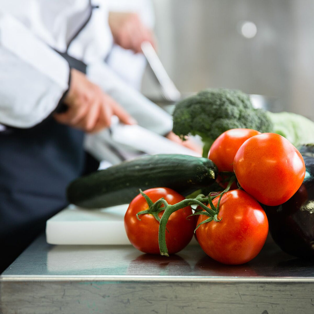 Fresh vegetables being prepared in a commercial kitchen with stainless steel countertop.